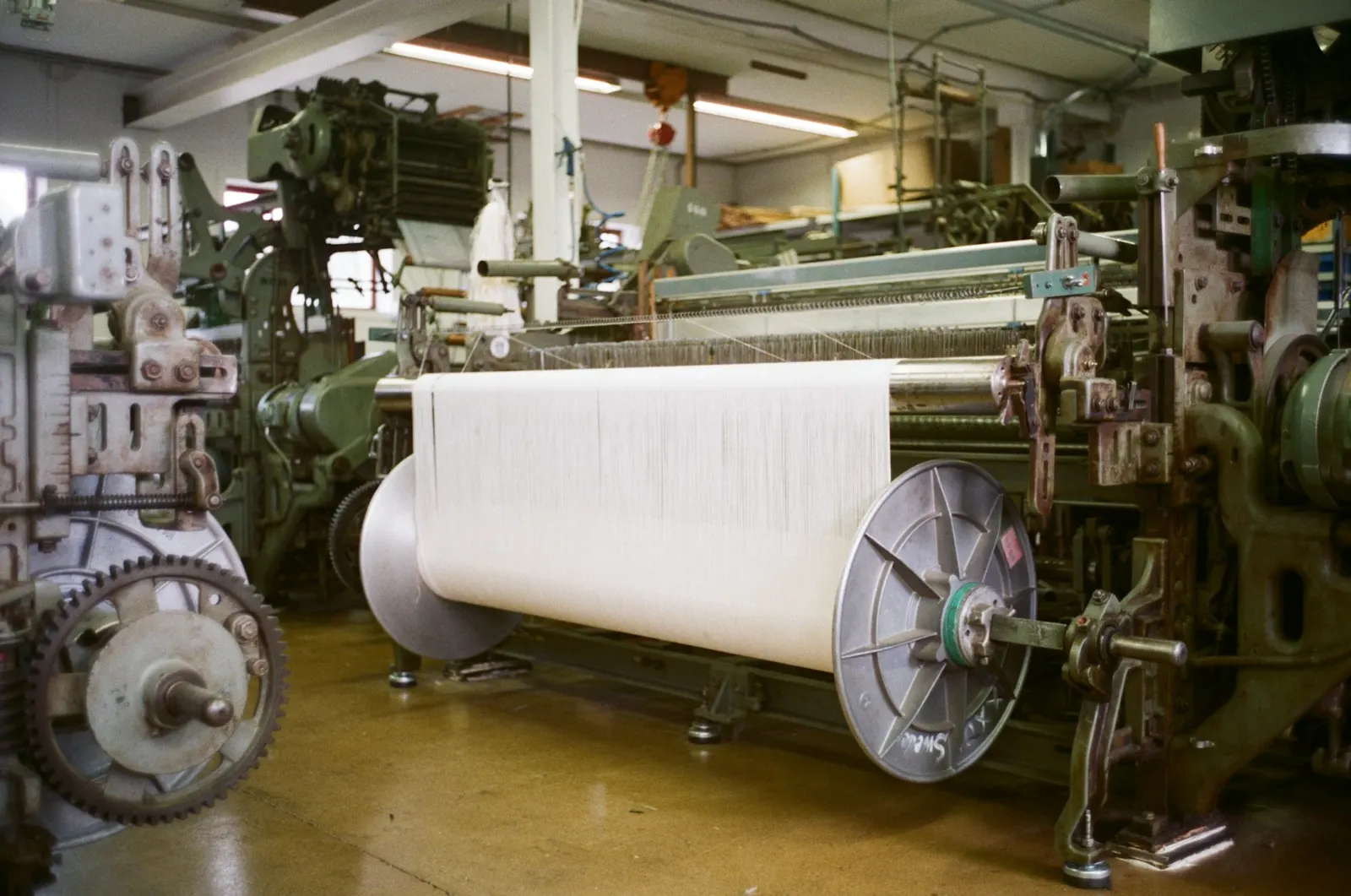 Telar industrial con un rollo grande de tela blanca